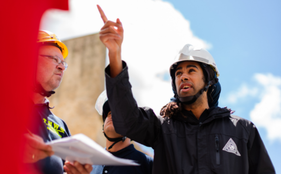 A worker in a hard hat points to something